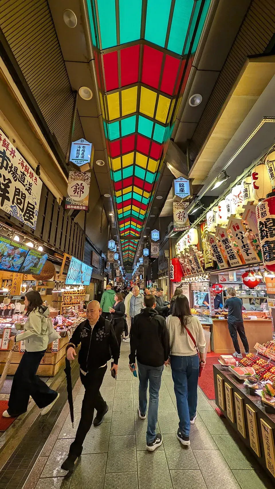 Shoppers under the colourful glass roof of Nishiki Market