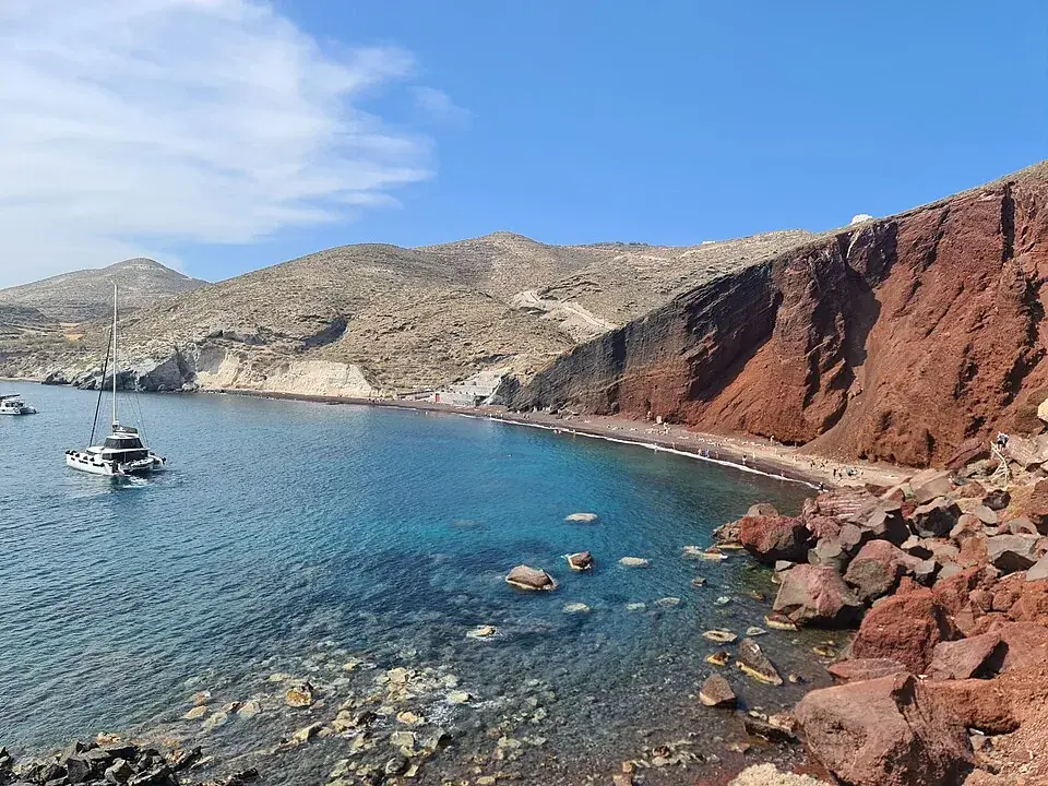 Red cliffs above the clear blue water of Red Beach on Santorini